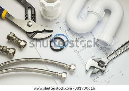 A selection of plumbing tools and fittings on house plans Royalty-Free Stock Photo #381930616