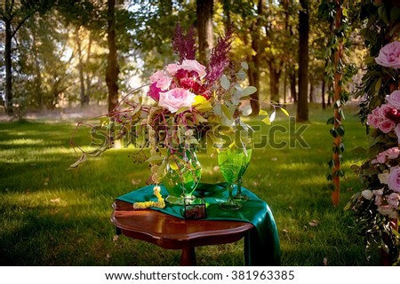 wedding bouquet, box with rings and wedding arch decorated with flowers  in deep summer forest. picture with soft focus