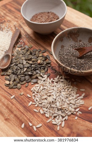 Mixed seeds in bowls with a wooden spoon and on wooden background. 
