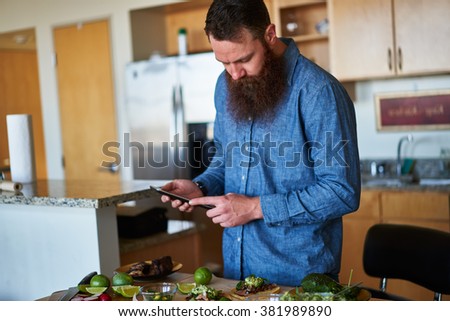 man making tacos in kitchen and using tablet to look up recipe shot with selective focus