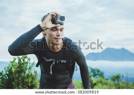 Attractive Traveler with Go PrO camera on his hand against the Batur volcano from Kintamani, Bali, Indonesia Royalty-Free Stock Photo #382009819