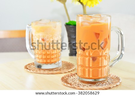 thai ice tea with milk in glass on the table and flower background
