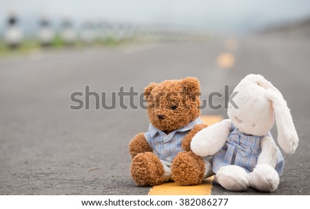 rabbit doll and brown bear toy sit on the road with hand together as love concept with light and vintage tone
