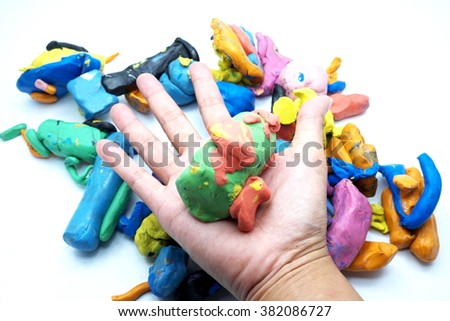 Pieces of plasticine with hand, isolated on white background. Focus on pieces on hand. Space for texts.