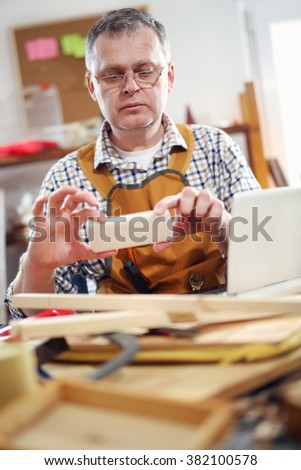 Portrait of carpenter sitting at his workshop use a mobile phone to take picture