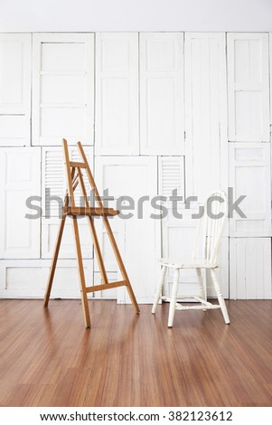 Vintage chair with paint stand in the room with white wooden window wall