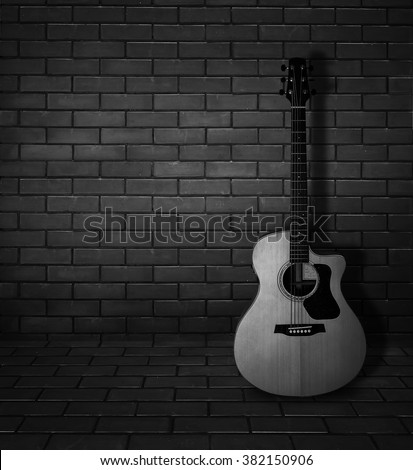 Acoustic guitar lay on the brick wall - black and white pic