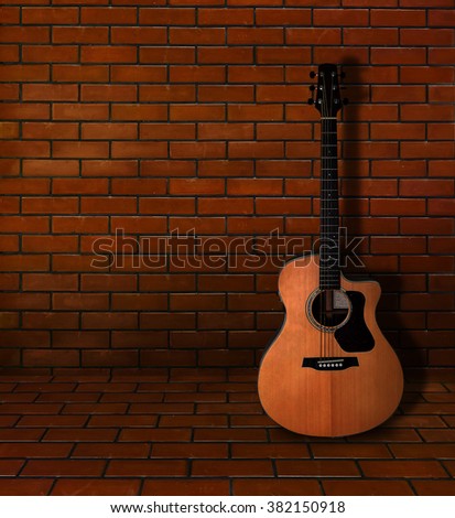 Acoustic guitar lay on the  brick wall 