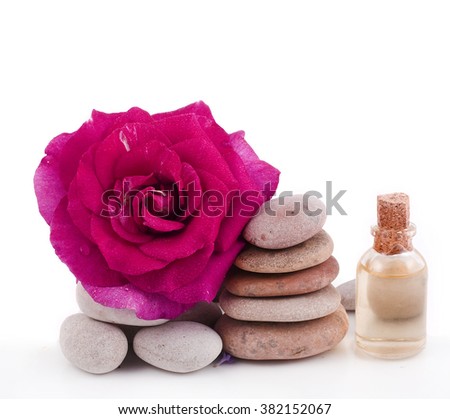 Spa stones with the rose flower and a bottle of essential oil isolated on a white background