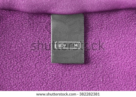 Black clothes label on pink fleece as a background