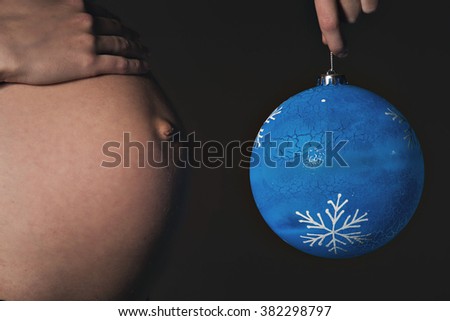 belly of a pregnant woman close-up on a black background with a clock