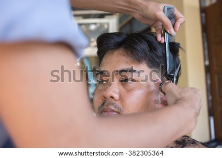 Fat Man getting a haircut by a hairdresser at his house.