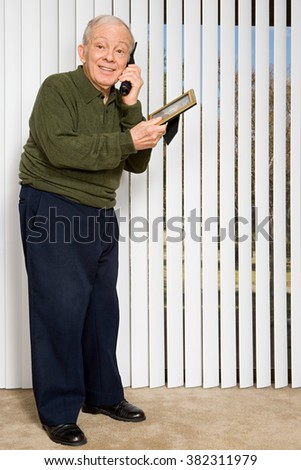 Elderly man on telephone holding picture frame