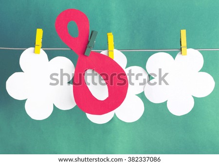 figure 8, paper flowers hang on clothespins in front of green background. International Women's Day. March 8, Happy Women's Day greeting message text