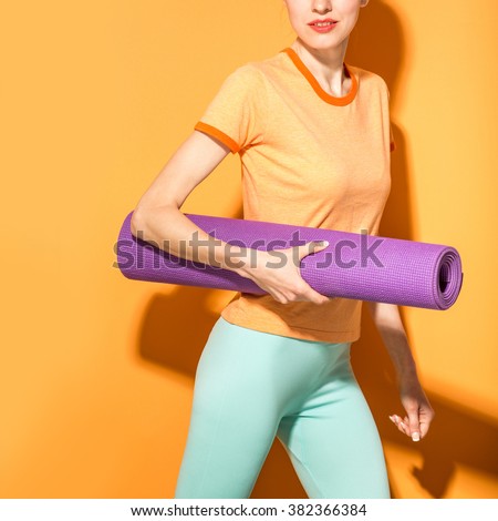 Yoga girl with a yoga mat over orange vibrant background