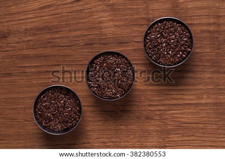 Photo of linseed in metal bowl on brown wooden table