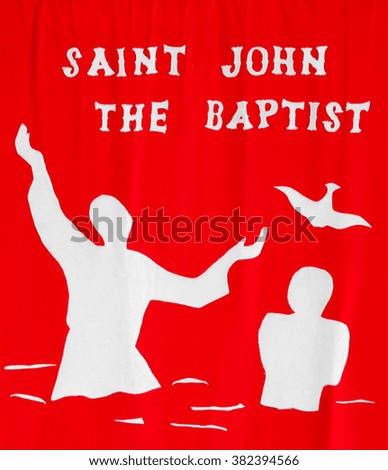 Saint John The Baptist text and symbol on red cloth.