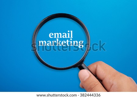 Email marketing. Hand holding magnifying glass focusing on the words.