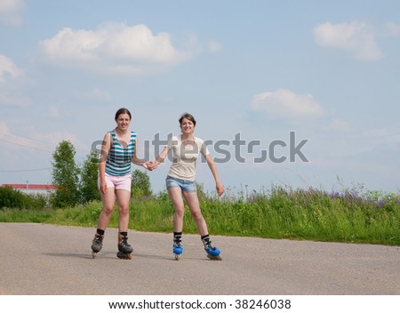 Two young females rollerskating on asphal road
