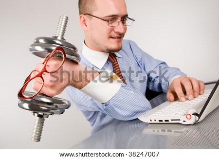 Businessman lifting dumbbell with laptop