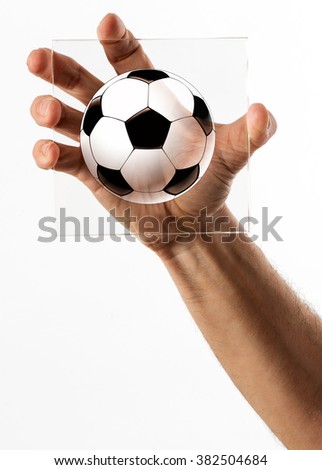 Single human hand holding a square piece of glass with a black and white soccer ball cartoon in the middle on white background