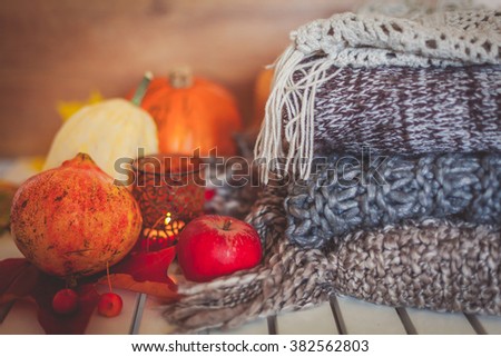 Still life decoration made with pumpkins, apples, pomegranate, woolen scarves and candle