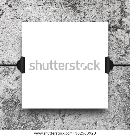 Close-up of one hanged square paper sheet frame with clips on grey concrete wall background