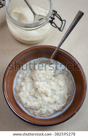 Bowl of porridge with a spoon and a kilner jar with sugar to top of image