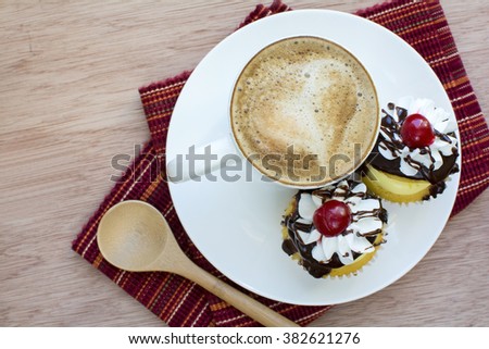 Cappuccino and boston cream cupcakes dessert in white plate on red strip placemat and wood background, Cappuccino coffee and boston cream cupcakes