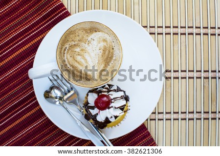 Cappuccino and boston cream cupcake dessert in white plate on folding red stripe placemat and stripe bamboo background, Cappuccino coffee and boston cream cupcake