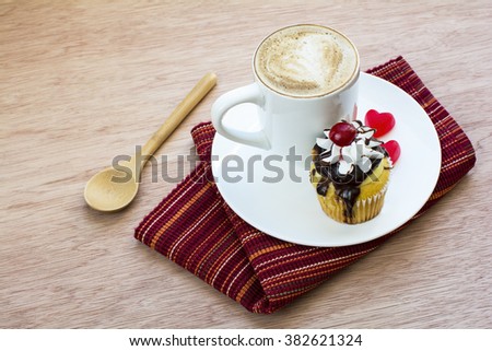 Cappuccino and boston cream cupcake dessert in white plate on folding red stripe placemat and wood background, Cappuccino coffee and boston cream cupcake 