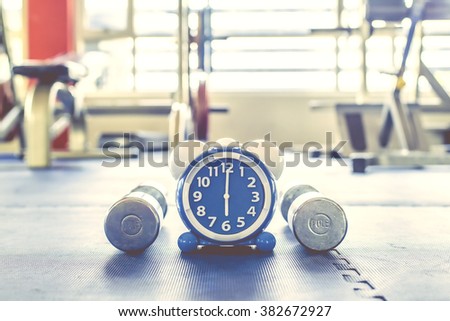 Time for exercising alarm clock and dumbbell  the Gym background. Share Time Exercise Healthy Concept Royalty-Free Stock Photo #382672927