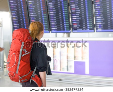 Young woman with backpack in airport near flight timetable Royalty-Free Stock Photo #382679224