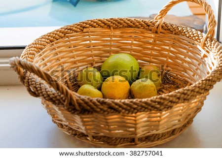Winter lingering apples lie in a basket on the windowsill country house windows.

