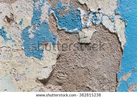 Close-up view a weathered damaged concrete wall with blue peeling paint and cracked stucco layer. Pattern of rustic blue grunge material from old wall seamless texture in an ancient town of Vietnam.