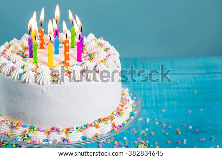 Buttercream birthday cake with colorful sprinkles and Candles over blue background