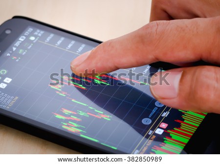 Trading on stock market with smartphone. Closeup photo.