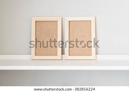 Wooden picture frame on the white shelf; Twin vertical picture frame 
