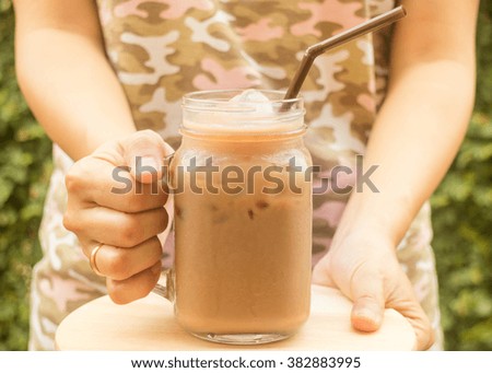 Hand hold glass of iced coffee with vintage filter effect, stock photo