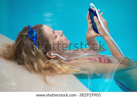Young female swimer is listening to music 
