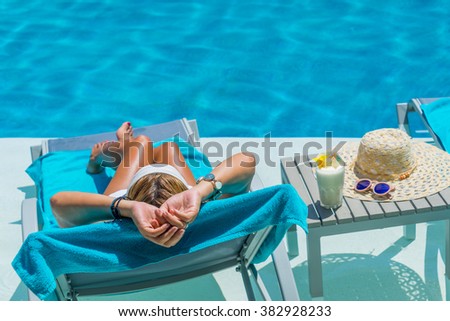 Pretty blond woman  enjoying a fresh cocktail in a swimming pool
