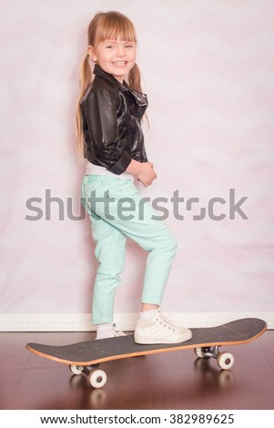 a little girl stands on skateboard on a light background