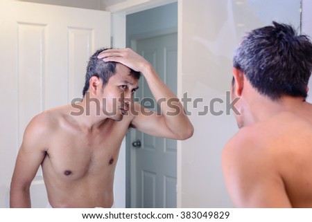 Man worried about gray hair while looking into a mirror. Royalty-Free Stock Photo #383049829