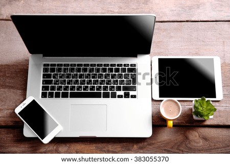 Modern laptop, smart phone and tablet on a wooden table