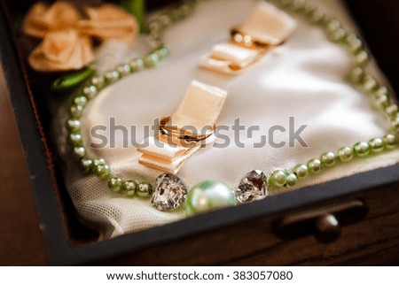 wedding rings in a box with a silk lining with green ornaments near