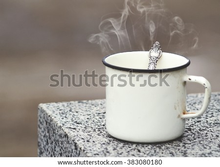 Old mug with a hot drink on a granite slab in the outdoors. Photo in vintage color image style. Coffee break outdoors.