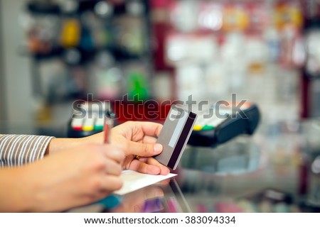 Woman holding credit card in hand, signing slip, in the store