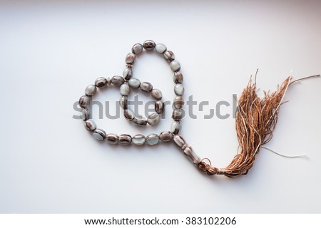 
rosary on a white background and the Koran . In the book it is written " Koran " Royalty-Free Stock Photo #383102206