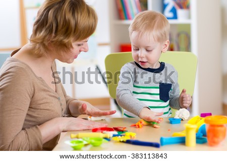 kid boy and mother play colorful clay toy in nursery