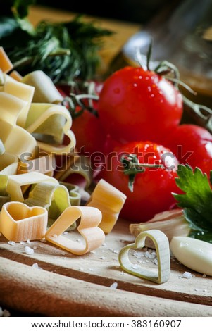 Spanish tricolor pasta corazones in the shape of hearts, cherry tomatoes, herbs, spices, salt, Mediterranean food, selective focus